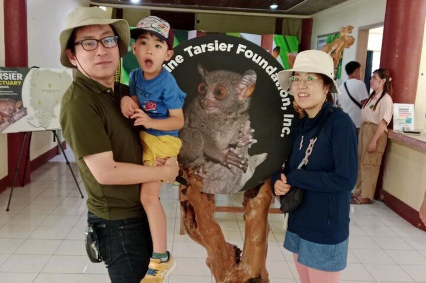 A person holding a child and a large poster with a tree and a koala. 5