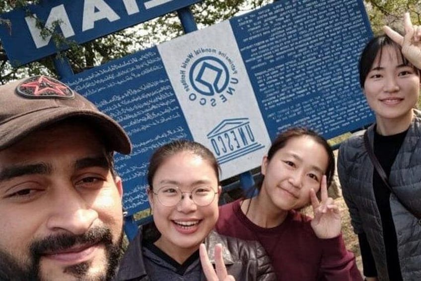 Un grupo de personas posando frente a un letrero con texto y logotipos. 2