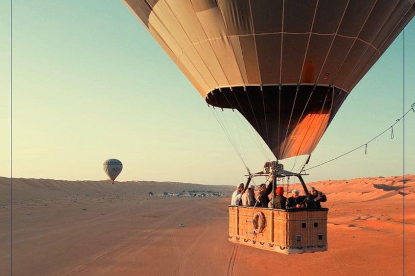 Une montgolfière survolant un paysage désertique, avec un groupe de personnes à l’intérieur. 2