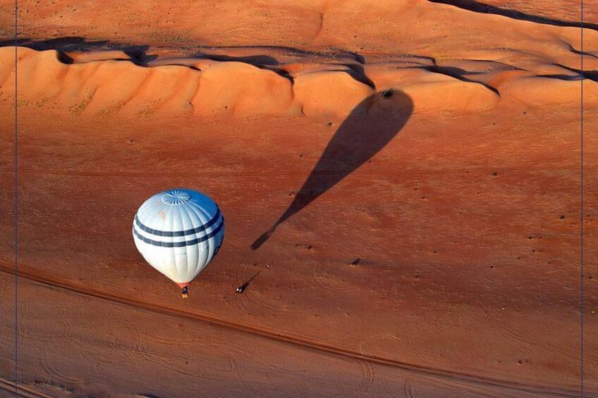 Une montgolfière survolant un paysage désertique avec des dunes de sable. 3