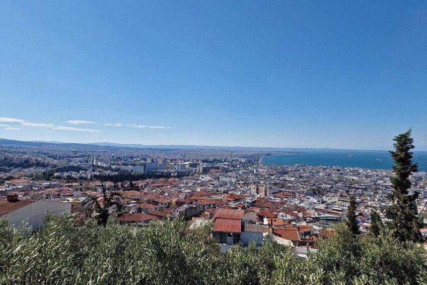 Un paysage urbain côtier avec des bâtiments aux toits rouges, un ciel bleu dégagé et une vue lointaine sur la mer. 2