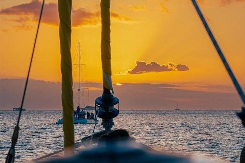 Solnedgang over havet med en sejlbåd og en anden båd i horisonten. 5