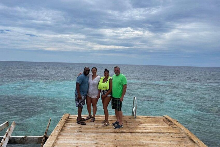 A wooden dock extending into a turquoise sea with a cloudy sky above. 5