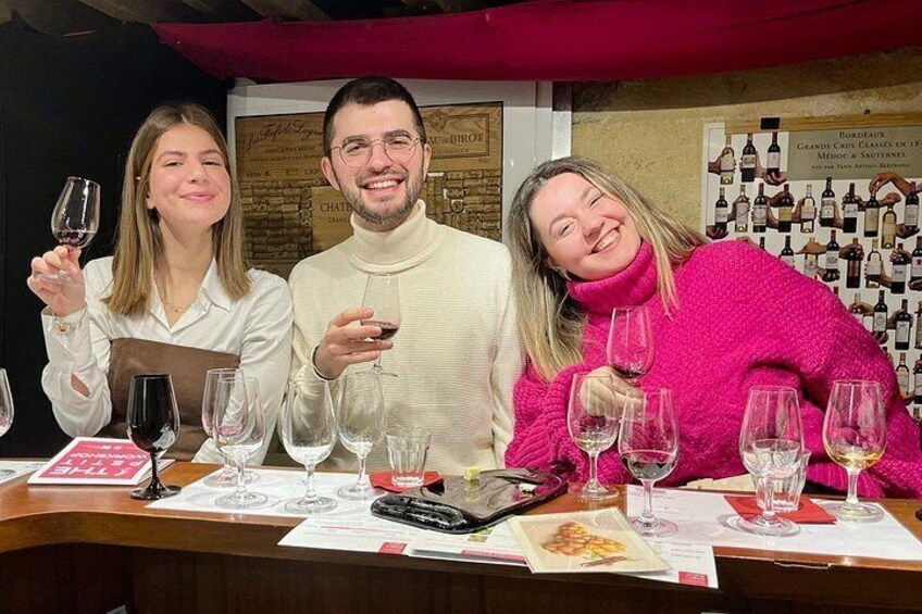 Three people at a wine tasting event with wine glasses and a menu. 5