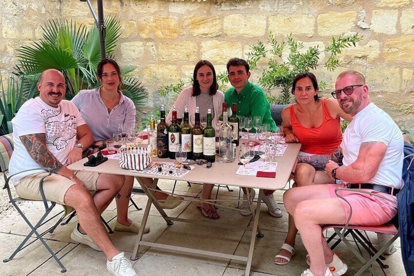 A group of people seated around a table with wine bottles and glasses. 2
