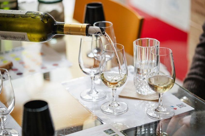 A wine bottle pouring wine into several glasses on a table. 5