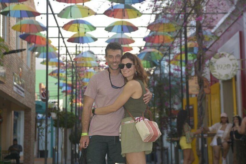 A couple embracing in a street with colorful umbrellas overhead. 4