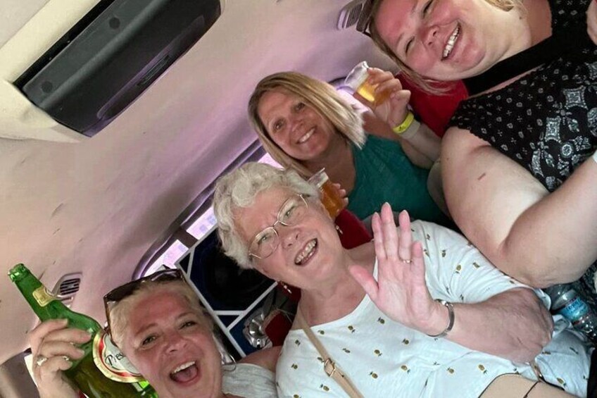 A group of people in a vehicle, some holding drinks. 1