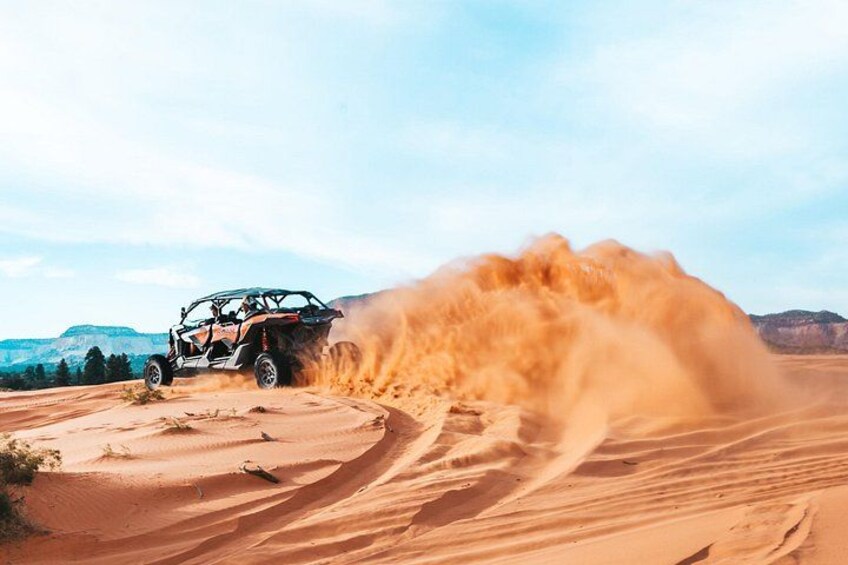 A vehicle driving through a desert with sand being kicked up. 3