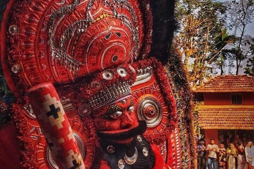 Un masque rouge et noir, richement décoré de motifs complexes et orné d’un symbole en forme de croix. 3
