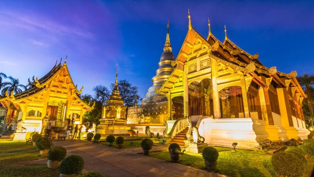 A temple complex with multiple pagodas and a central stupa, illuminated at dusk. 4