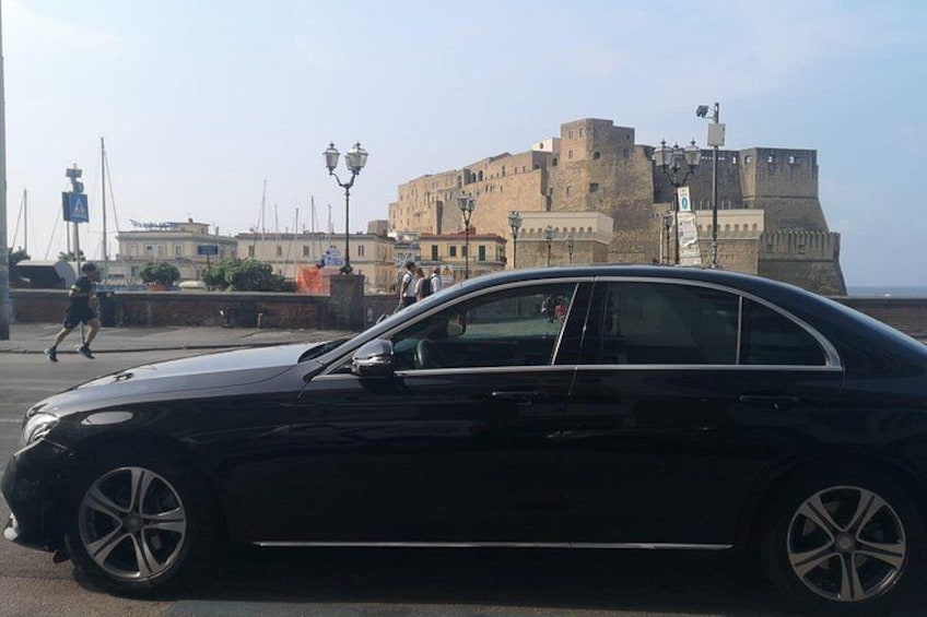 Un coche negro estacionado en una calle con un edificio histórico al fondo. 4