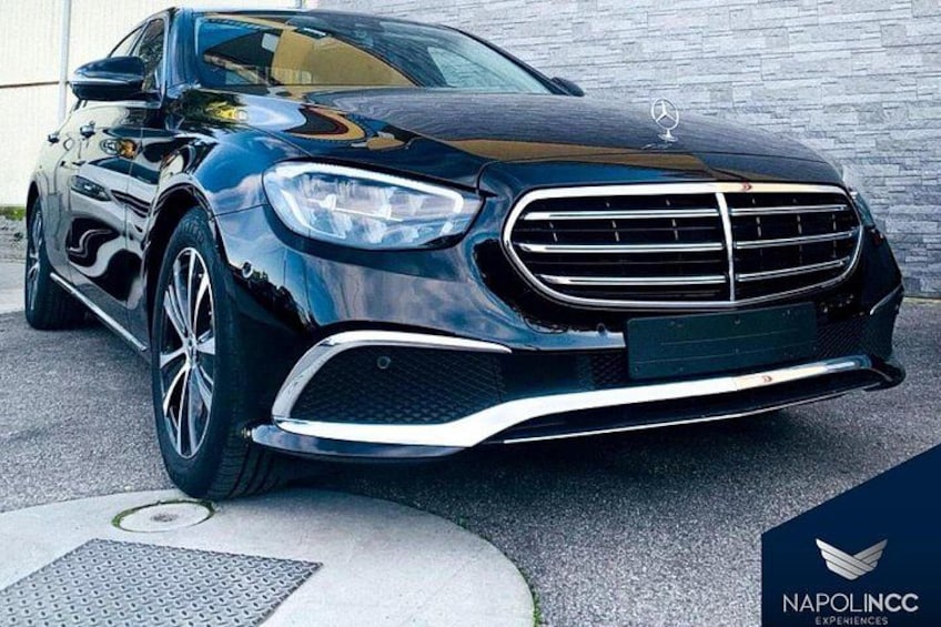Un coche de lujo negro estacionado frente a un edificio con un logotipo que dice 'NAPOLINCC EXPERIENCES'. 3