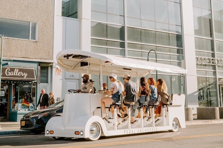 A vintage pedal-powered vehicle with passengers on a city street. 1