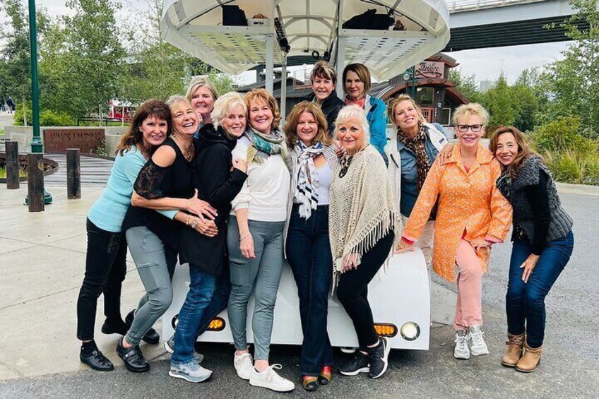 A group of people posing in front of a white bus with a curved roof. 4