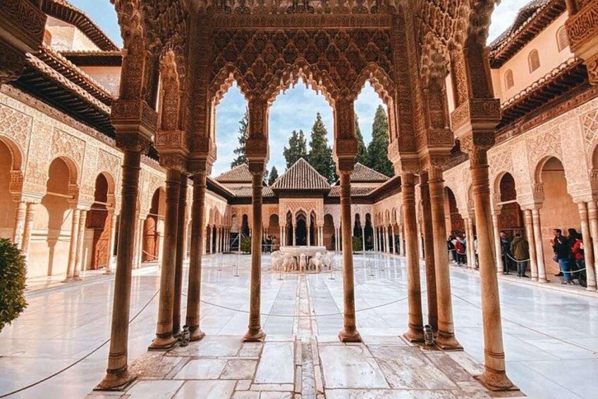 An ornate courtyard with arches and columns, a fountain, and a tiled floor. 1
