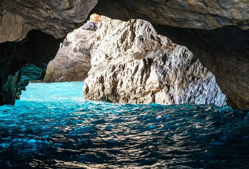 A rocky cave entrance with clear blue water. 2