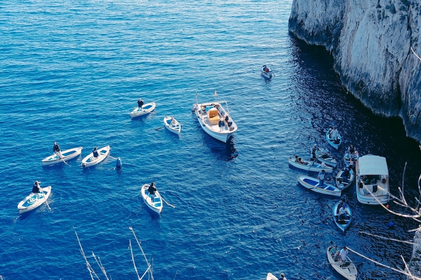 A group of small boats on a calm sea near a rocky coastline. 3