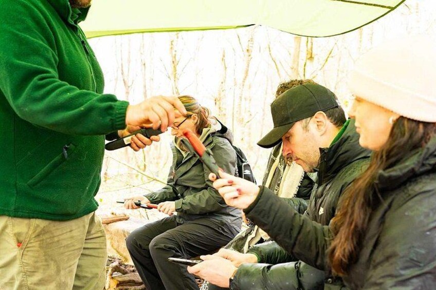 People in outdoor gear, possibly camping, with a tent and trees in the background. 4
