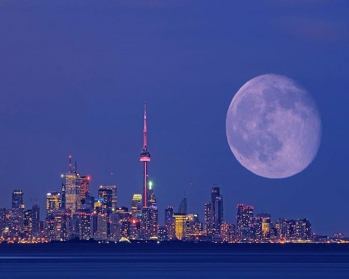 A city skyline with a prominent tower and a full moon in the sky. 3