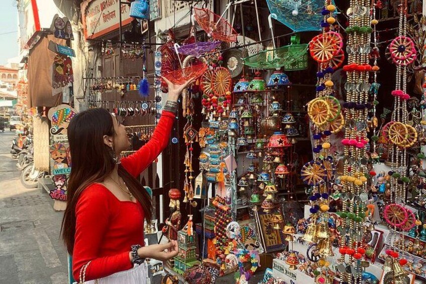 Una persona osserva uno scaffale di mercato pieno di piccoli oggetti colorati e decorazioni. 1