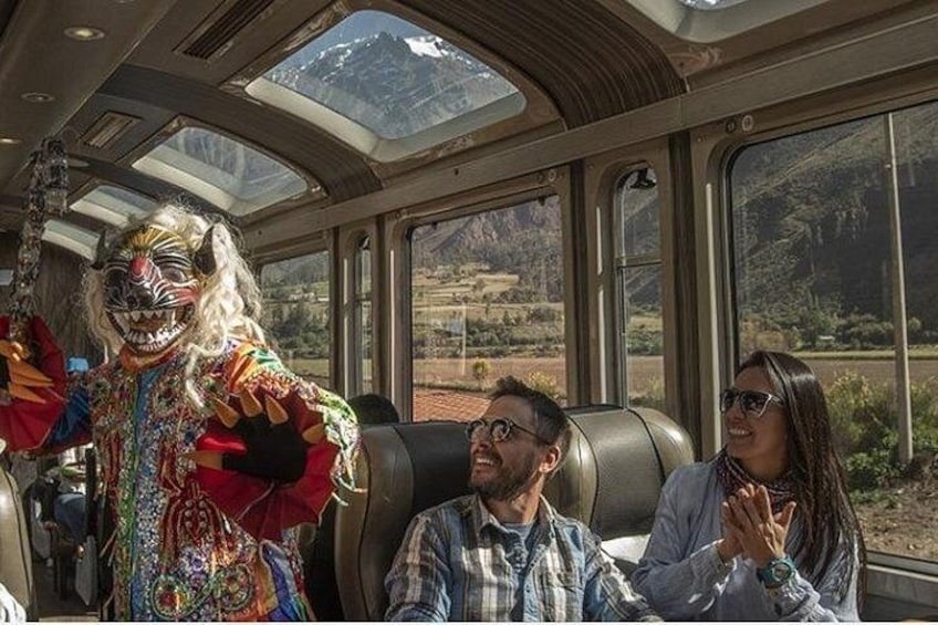 Interior de un tren con pasajeros y un artista vestido con traje tradicional. 4