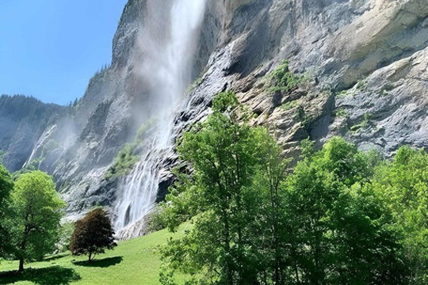 A waterfall cascading down a rocky cliff surrounded by lush green trees. 2