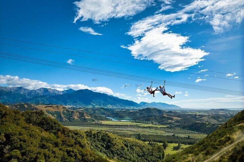 Iemand parachutes boven een bergachtig landschap met elektriciteitsleidingen en een heldere lucht. 1