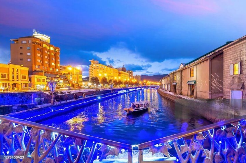 A river with a boat, buildings, and a bridge. 1