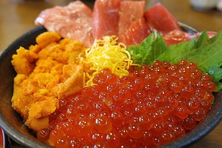 A bowl of sushi with salmon, tuna, and orange fish roe. 2