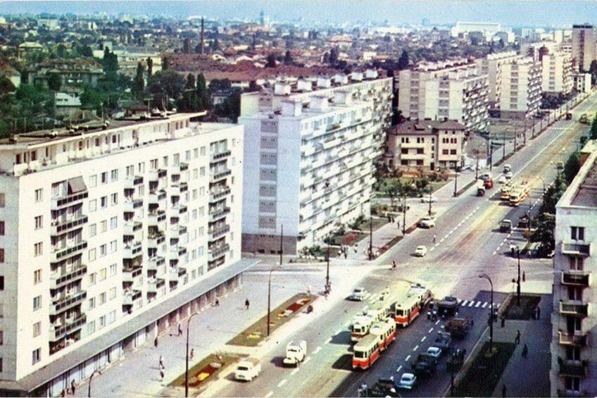 Un horizonte urbano con edificios altos, una calle concurrida con coches y autobuses, y un cielo despejado. 3
