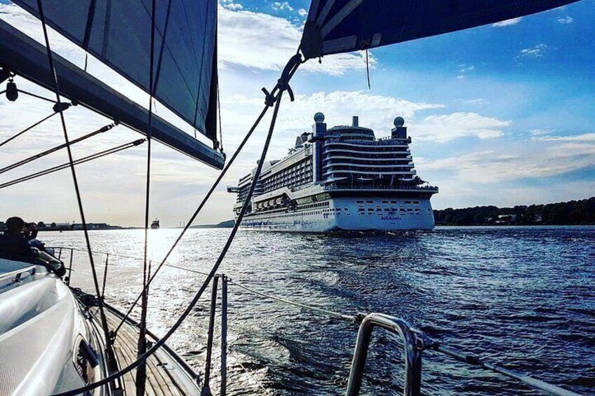 Un crucero en el agua con un velero al frente. 2