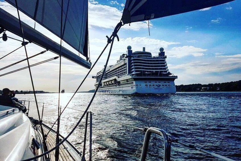 A cruise ship on the water with a sailboat in the foreground. 4