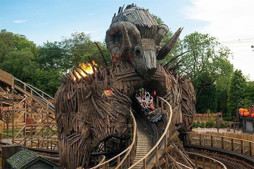 Une piste de montagnes russes en bois qui serpente à travers une grande structure ressemblant à un arbre, dont le design évoque un dragon. 1