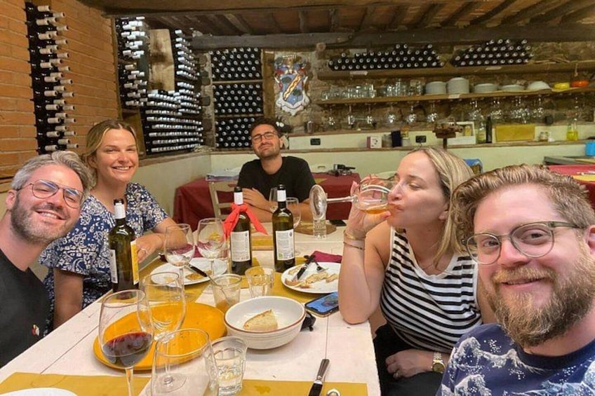 A group of people dining at a table with wine bottles and glasses. 4