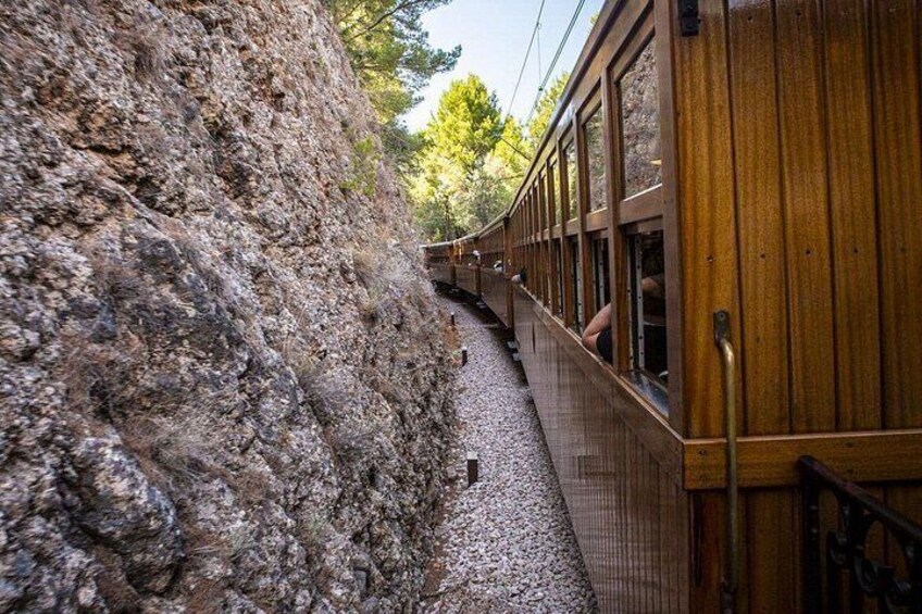A train traveling through a rocky terrain with wooden siding and gravel. 3