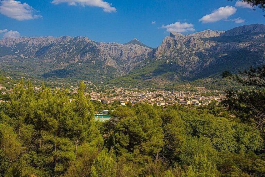 A town nestled among mountains with dense green forests in the foreground. 2