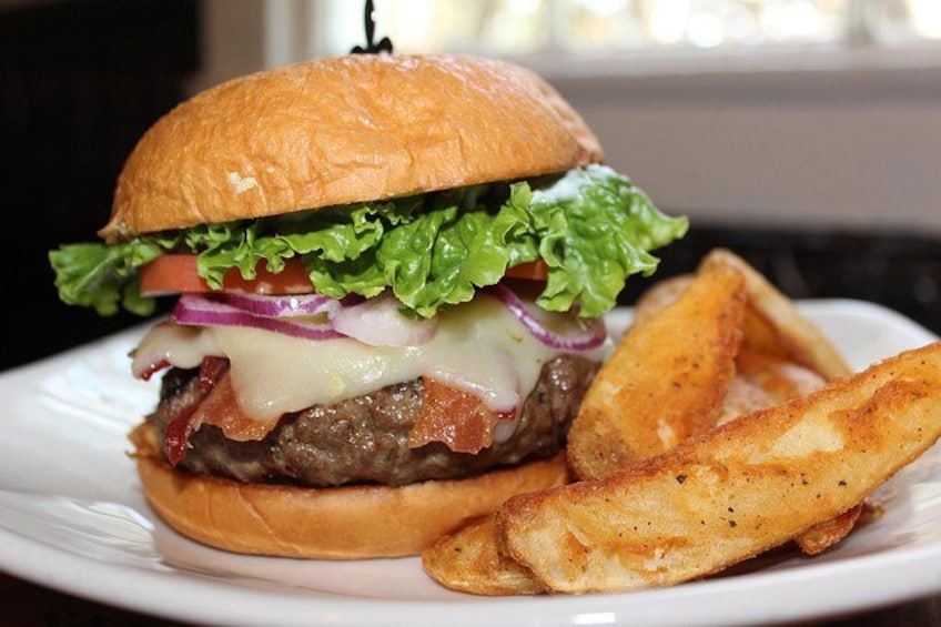 Hamburguesa con lechuga, tomate, cebolla y queso, acompañada de papas fritas sobre un plato blanco. 5