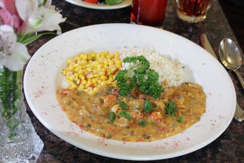 A plate of food with corn, rice, and a stew, garnished with parsley. 2
