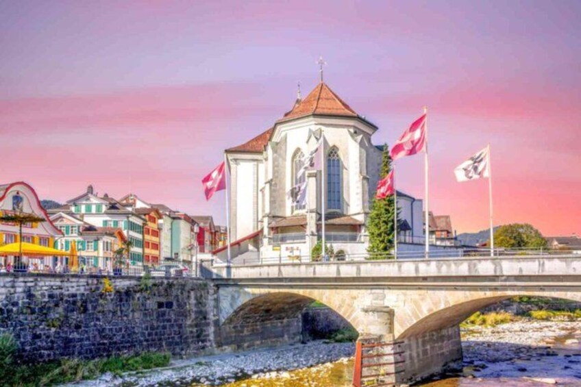 A bridge with a white building on top, flags, and colorful buildings in the background. 4