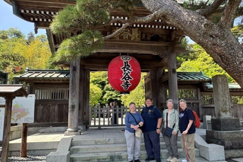 Ein traditionelles japanisches Tor mit einem roten Laternenleuchter, Holzsäulen und einem steinernen Weg. 4