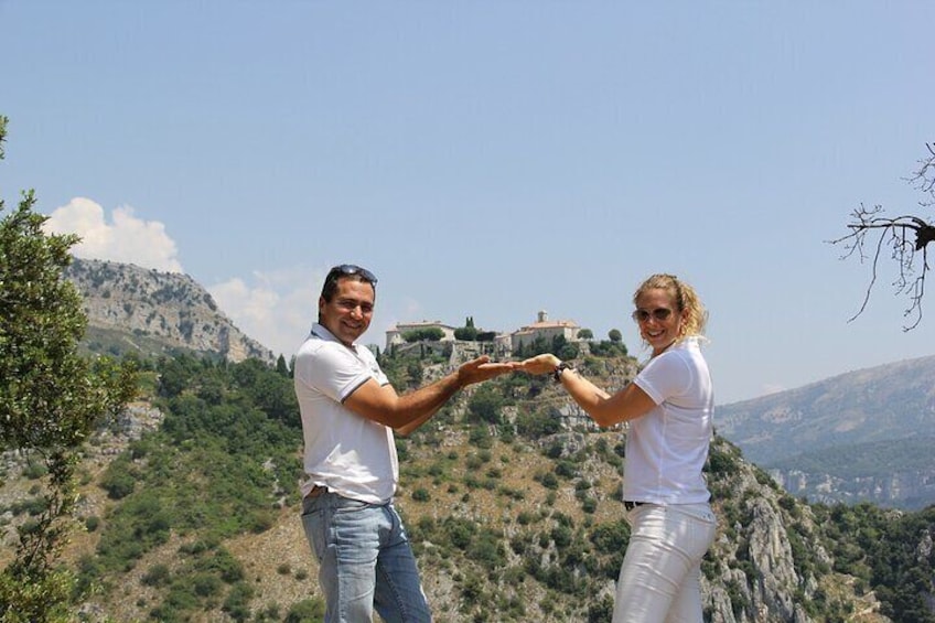 Two people forming a heart shape with their hands against a mountainous backdrop. 1