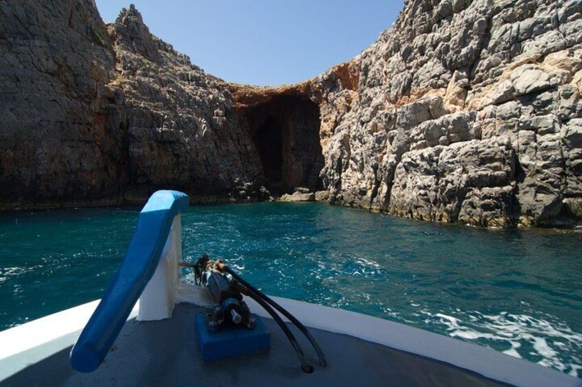 Una embarcación en una cala rocosa con aguas azul cristalino y un estrecho paso entre grandes formaciones rocosas. 2