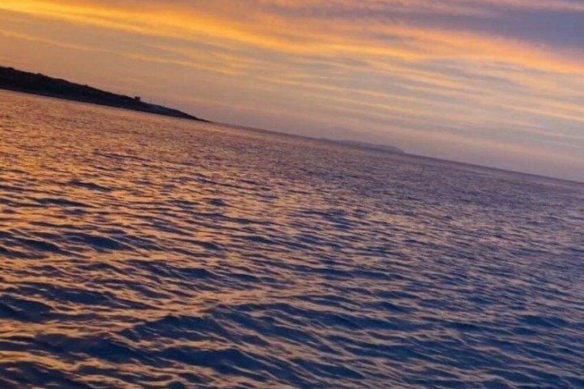 A body of water with a distant shoreline and a sunset sky. 2