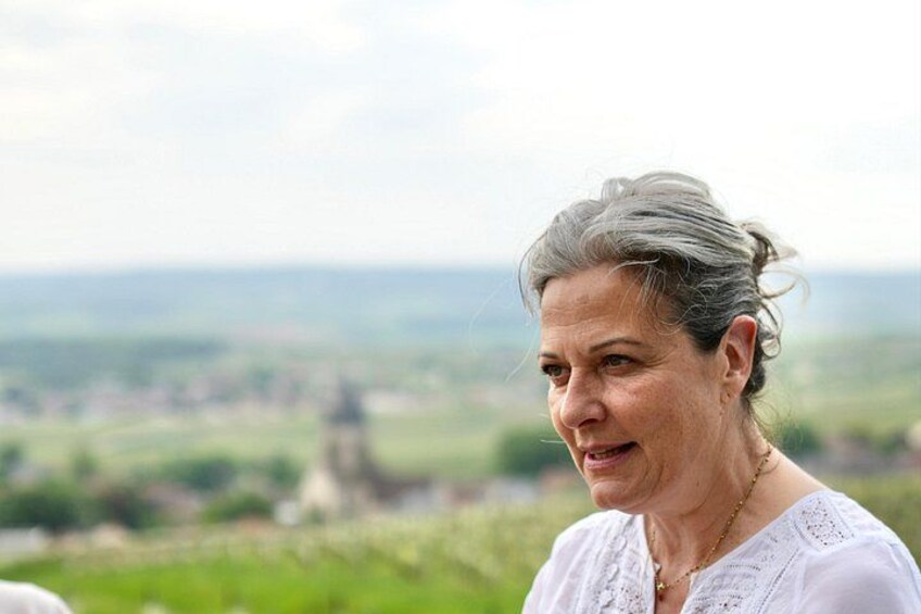 Una persona con una blusa blanca y un paisaje de fondo. 3