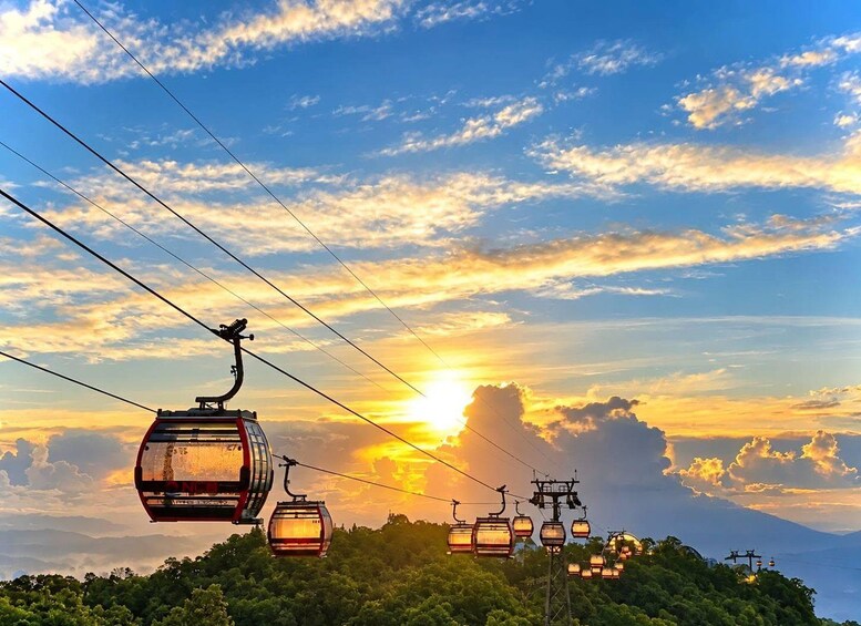 A cable car system with multiple gondolas against a sunset sky. 1