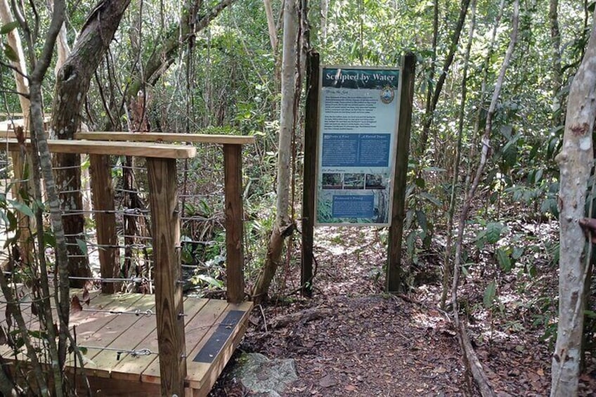 A wooden platform with a sign in a forested area. 1