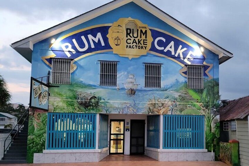 Un bâtiment orné d’une fresque représentant une usine de fabrication de gâteaux au rhum, d’une enseigne indiquant « gâteaux au rhum », et d’une clôture bleue. 3