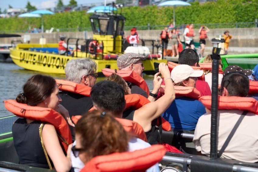 People on a boat wearing life jackets, a yellow boat in the background, and a person in a white hat. 2