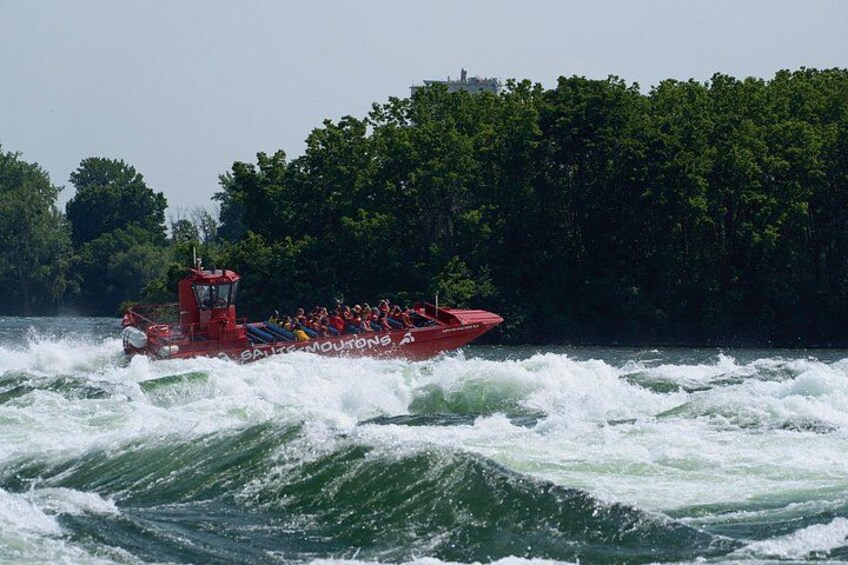 A red boat with passengers navigating through choppy waters. 3